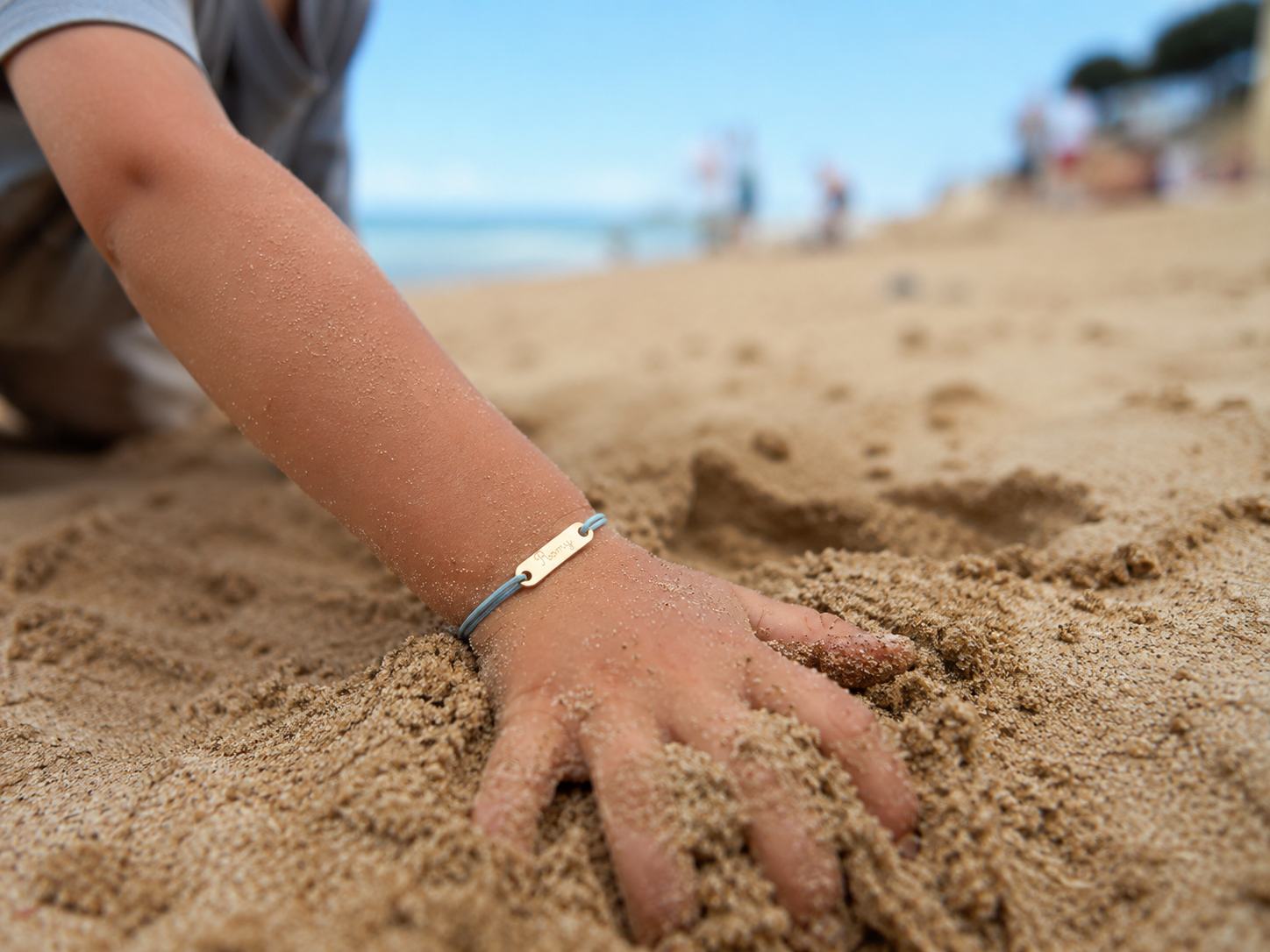 Bracelet Bobiin personnalisé au poignet d'un enfant, posé dans le sable
